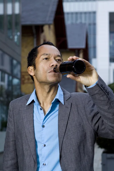Smart casual üzleti ember iszik sört szabadban álló modern előtt — Stock Fotó