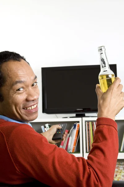 Hombre de negocios casual inteligente sentado en el sofá bebiendo cerveza con control remoto en hi — Foto de Stock