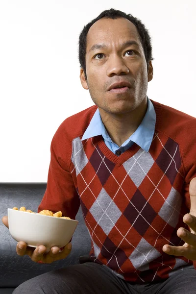 Man nibbling while watching television Stock Picture