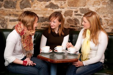 Three beautiful young students waiting drinking coffee and havi clipart