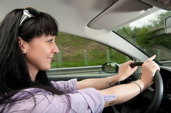 stock image Beautiful young woman drives a car on a highway