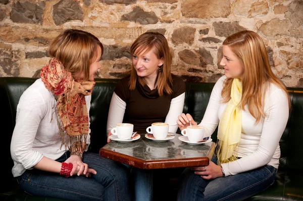 Drie mooie jonge studenten drinken koffie en havi wachten — Stockfoto