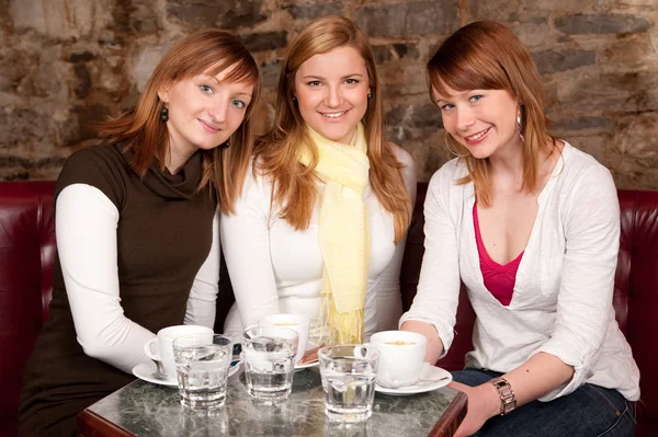 Drie mooie jonge studenten drinken koffie en havi wachten — Stockfoto
