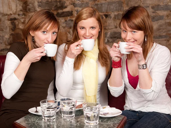 Three beautiful young students waiting drinking coffee and havi — Stock Photo, Image