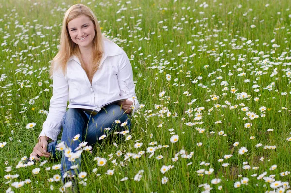 Krásná mladá žena čtení knihy venku na tráva pole i — Stock fotografie