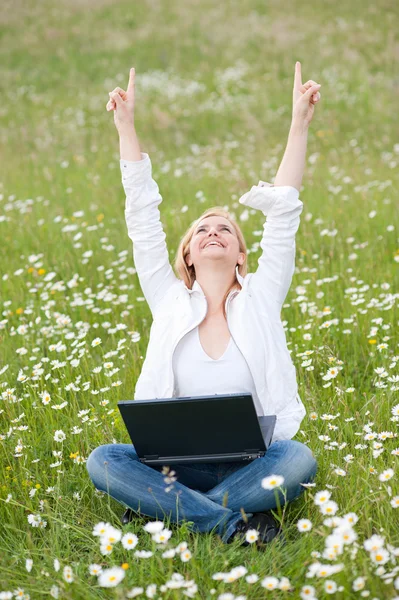 Девушка с ноутбуком на травяном поле в парке — стоковое фото