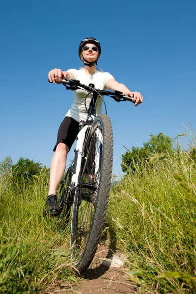 stock image Young girl riding a bike on a field path - offroad