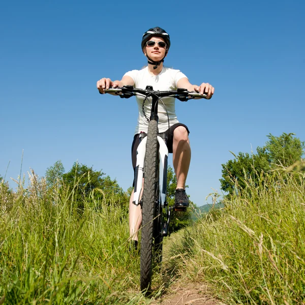 stock image Young girl riding a bike on a field path - offroad