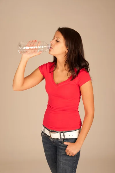 Jolie jeune femme en t-shirt rouge et jeans à boire en bouteille — Photo
