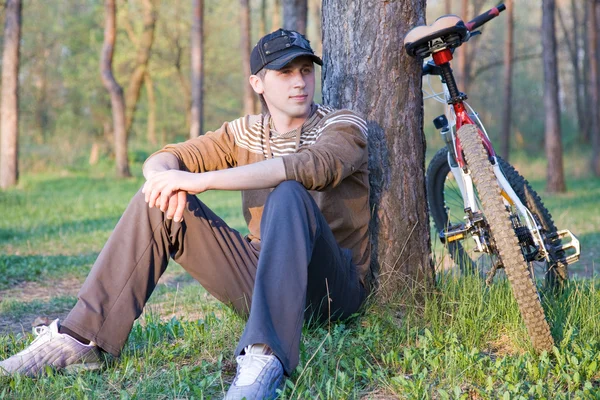 stock image Mountain biker resting in forest on a grass