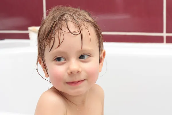 Linda niña de tres años de edad, mirando desde un baño y sonriendo — Foto de Stock