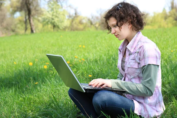 Meisje met een laptop op de lente weide — Stockfoto