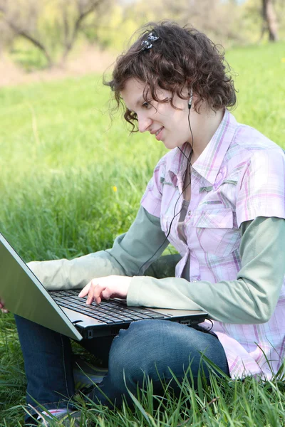 Meisje met een laptop op de lente weide — Stockfoto