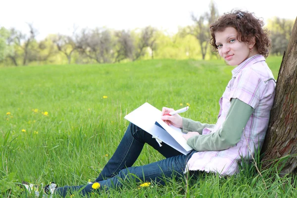 Ragazza studente nel parco scrive nel libro di scrittura — Foto Stock