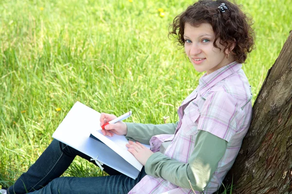Meisje student in park schrijft in het schrijven boek — Stockfoto