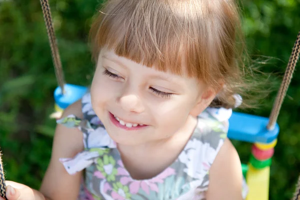 Happy little girl on a swing looking up — Stock Photo, Image