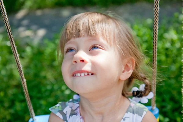 Glückliches kleines Mädchen auf einer Schaukel, das nach oben schaut — Stockfoto