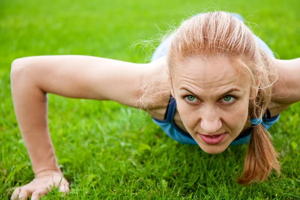 Kaukasische vrouw doet push ups in het park — Stockfoto