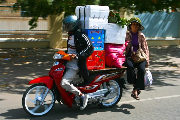 Sterownik motocykl z pasażerem wykonuje pola w phnom penh, Kambodża. — Zdjęcie stockowe