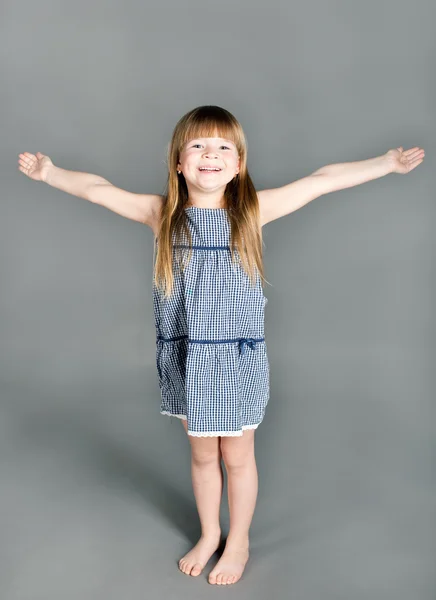 The little girl in a dress smiles spreading his hands — Stock Photo, Image