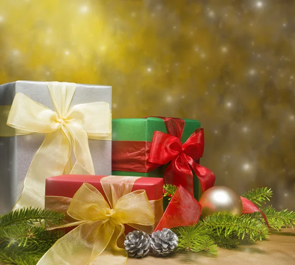Three presents decorated with gold satin and Christmas decoratio — Stock Photo, Image