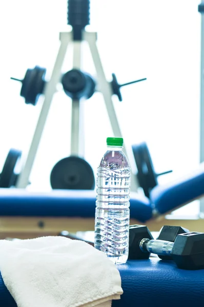 Gewichten stand, Bank van een fitnessruimte met een handdoek en water fles — Stockfoto