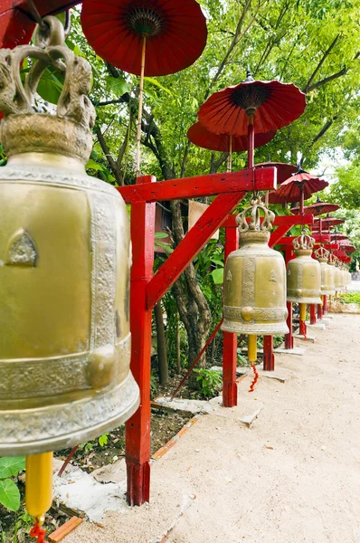Ряд колоколов в храме, покрытый красным зонтиком — стоковое фото
