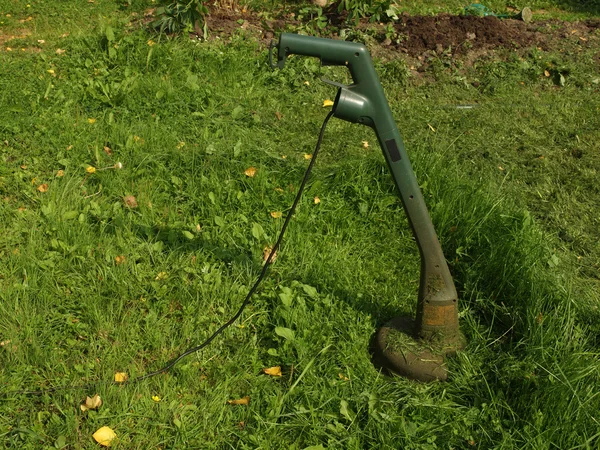 Cortadora de césped eléctrica en una hierba oblicua . — Foto de Stock