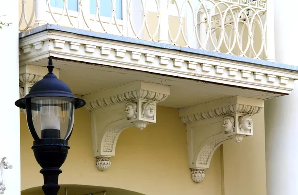 Un viejo balcón decorado con hermosas cabezas de mujer y una lámpara de calle — Foto de Stock