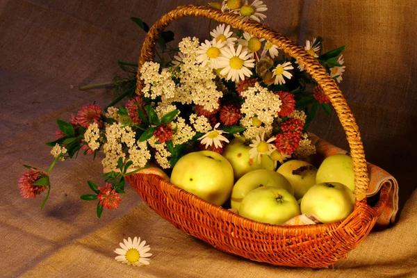 Reife Äpfel und Blumen im Korb — Stockfoto