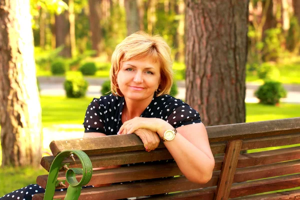 Hübsche Geschäftsfrau sitzt auf einer Bank und lächelt — Stockfoto