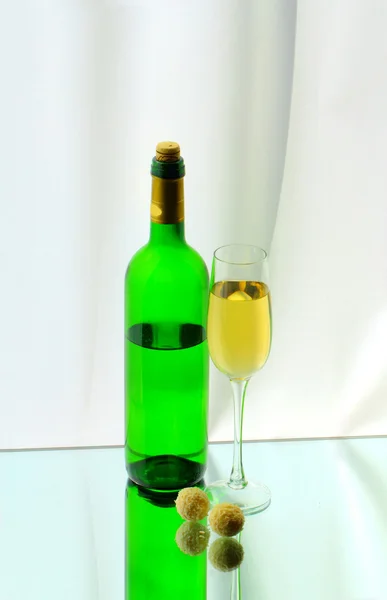 Um copo de vinho, uma garrafa e dois doces — Fotografia de Stock