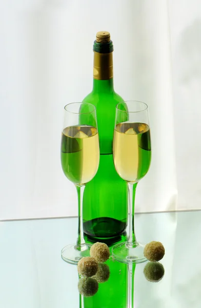 Due bicchieri da vino, una bottiglia e caramelle sullo specchio — Foto Stock