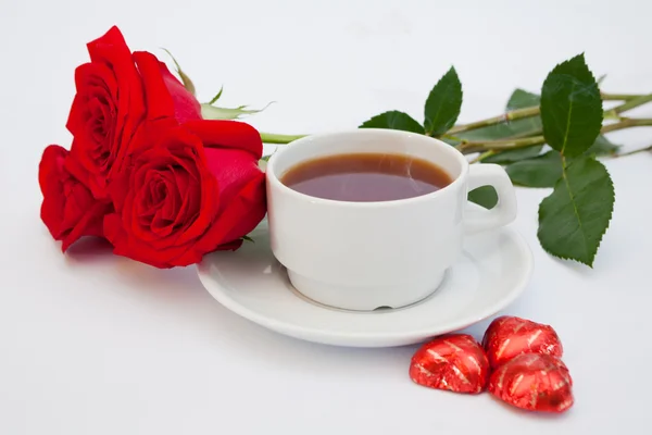 Stock image Bouquet of red roses next to a cup of tea