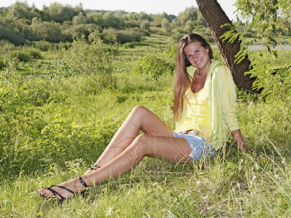 Una hermosa chica sentada en la hierba — Foto de Stock