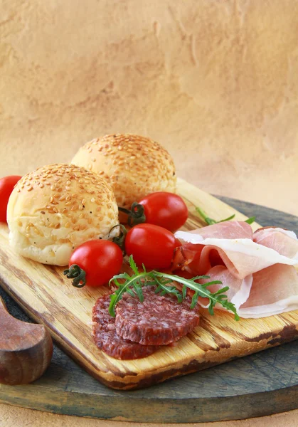 Sortidas vários tipos de salsichas e carnes defumadas em uma placa de corte — Fotografia de Stock
