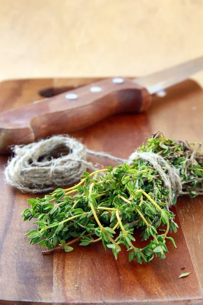 Bunch of fresh thyme and a knife on a wooden board — Stock Photo, Image