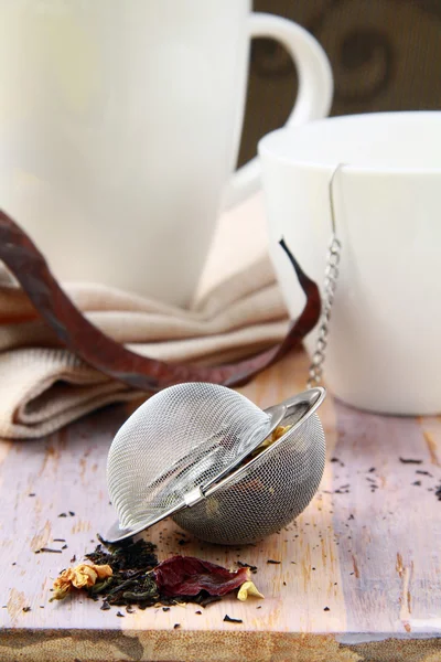 Theezeef met een geurige zwarte thee en bekers in de achtergrond — Stockfoto