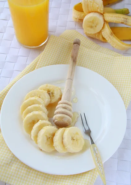 Banán szeletekre vágva egy tányérra, mézzel — Stock Fotó