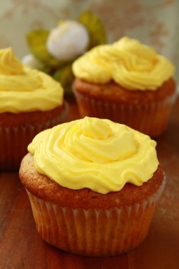 ahşap bir masa üzerinde sarı kremalı cupcake