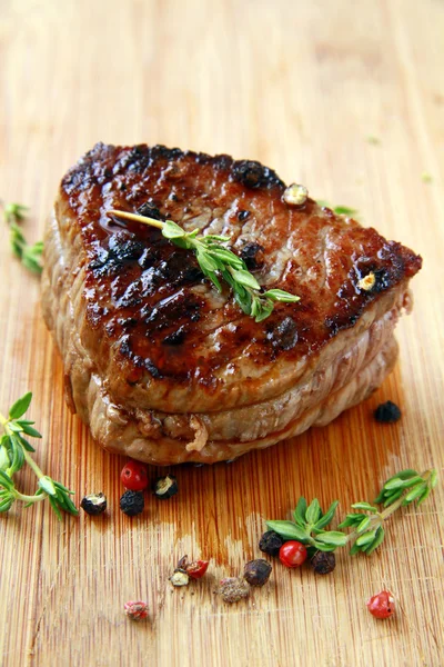 Juicy sirloin beef with branches of thyme covered in pepper — Stock Photo, Image
