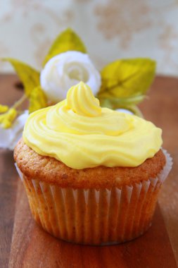 ahşap bir masa üzerinde sarı kremalı cupcake