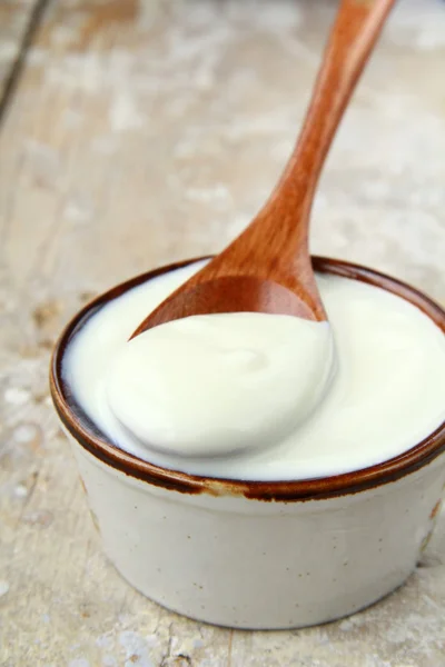 โยเกิร์ตธรรมชาติสดในถ้วยเซรามิกบนโต๊ะไม้ — ภาพถ่ายสต็อก