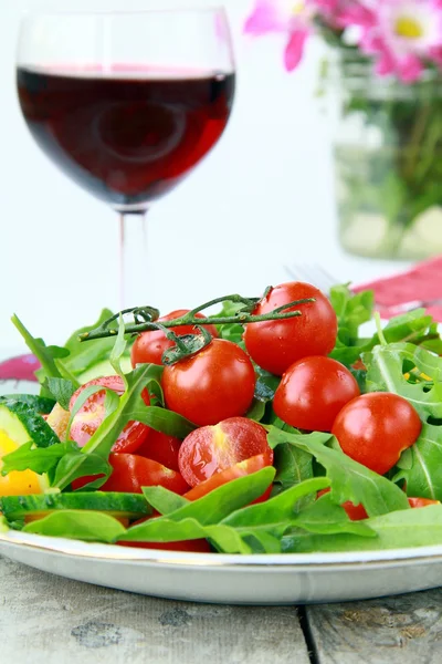 Sałatka z rukolą i pomidorami koktajlowymi przy lampce wina w backgrou — Zdjęcie stockowe