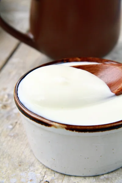 在木桌子上一个陶瓷杯新鲜天然酸奶 — 图库照片