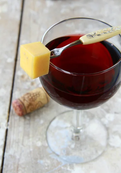 おやつチーズのスライスと赤ワインのガラス — ストック写真