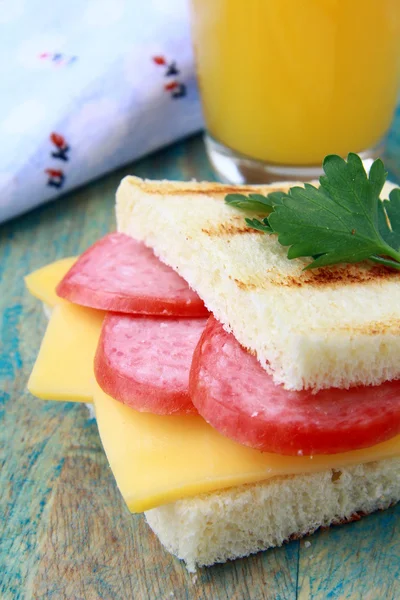 Breakfast sandwich with cheese and salami and juice — Stock Photo, Image