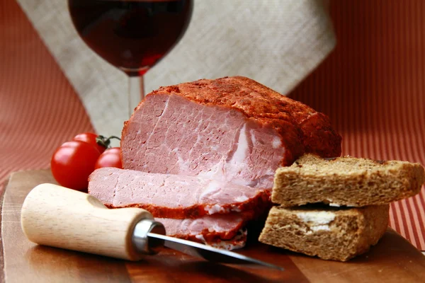 Groot stuk van ham in peper met een glas rode wijn — Stockfoto