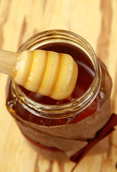 Tarro con miel y cuchara de madera para miel sobre fondo marrón — Foto de Stock