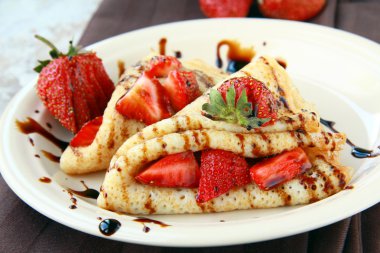 Sweet thin french style crepes, served with strawberries,chocolate sauce clipart